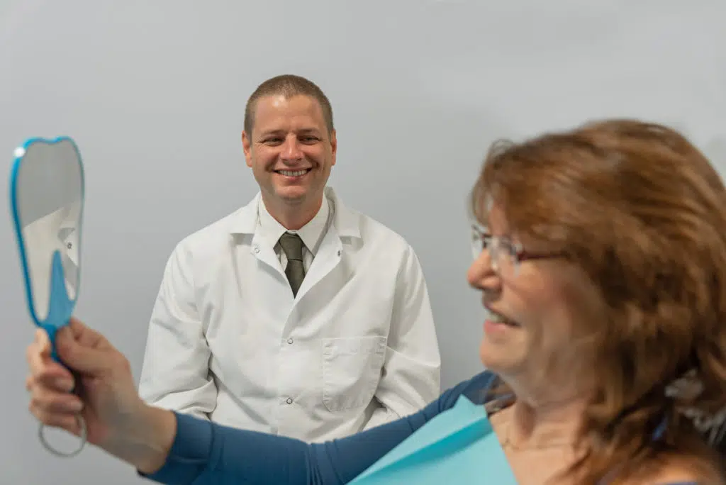 our dentist in Troy, IL, with a smiling patient after prosthodontic treatments at our dental office.